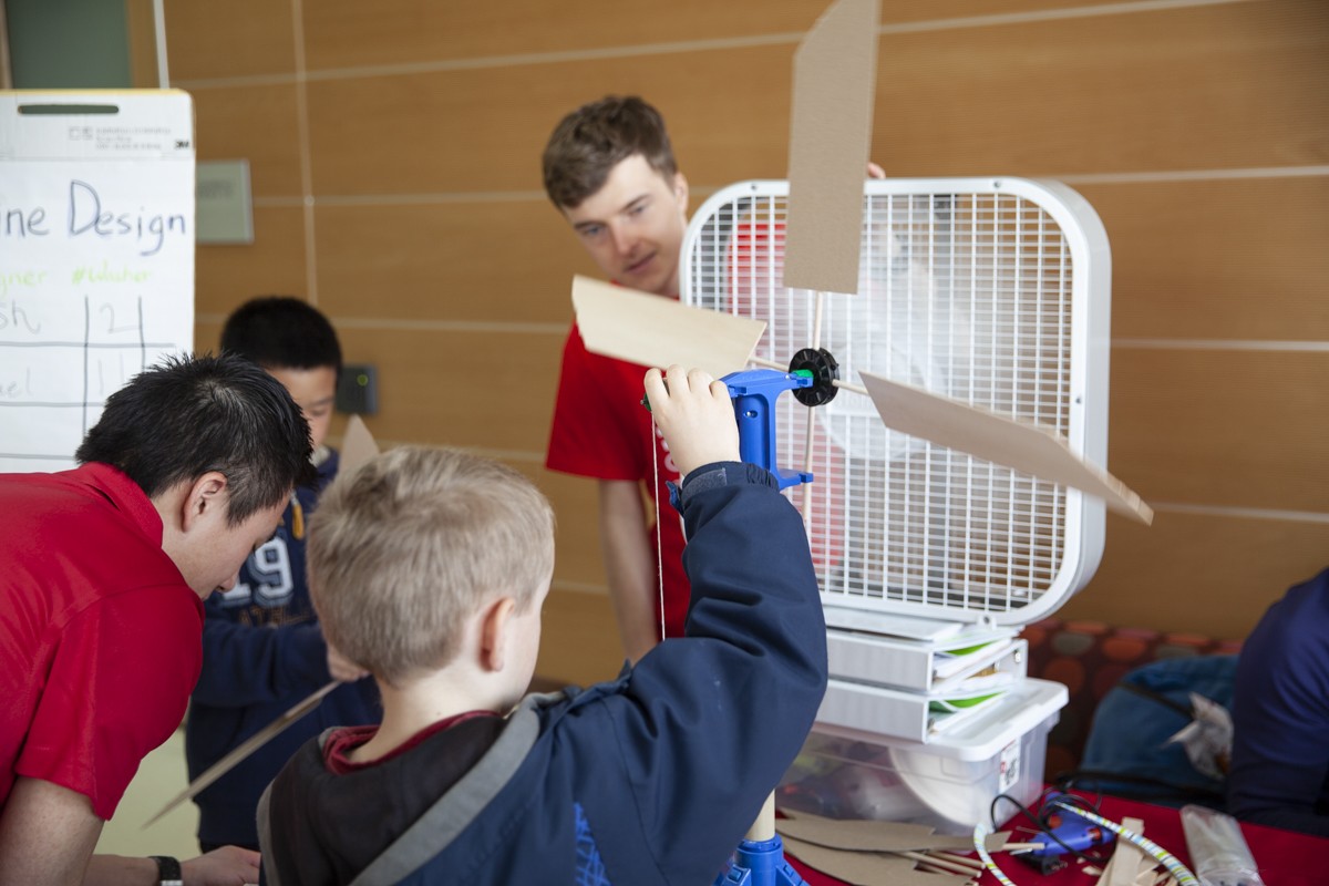 Students test wind turbine designs in front of a fan.