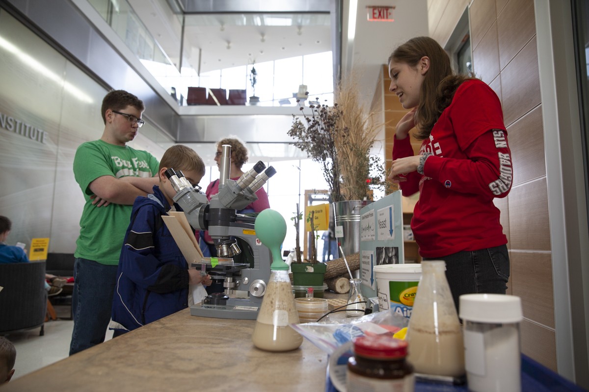 Students look into a microscope while a fermenting solution bubbles beside them.