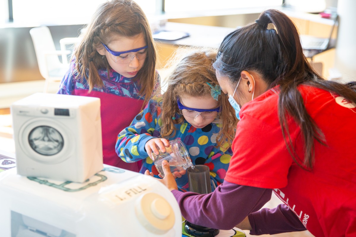 Two girls pour water as part of the Plastic Panic exploration station.