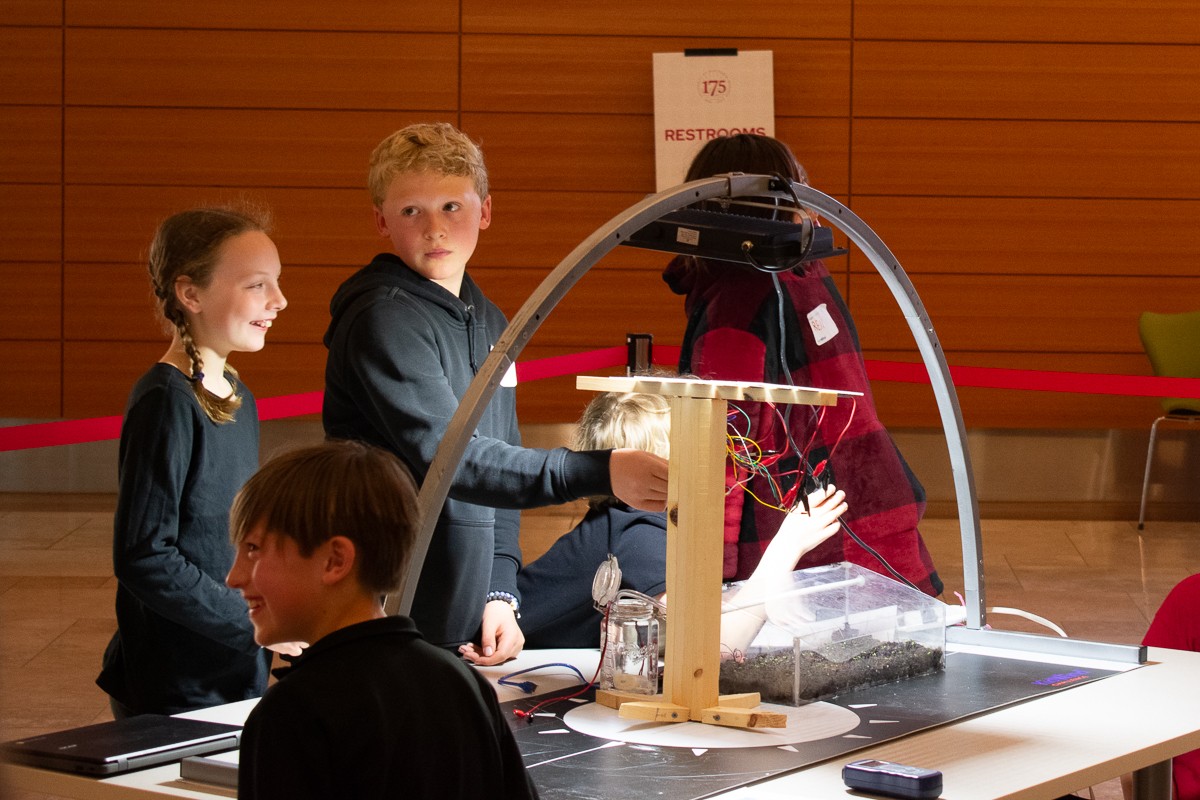 Students demonstrate their solar device under the solar arch.