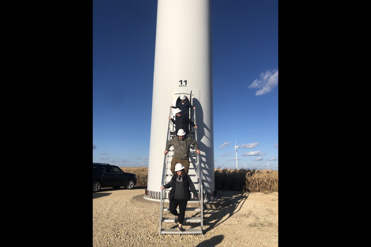 Educators climb down from the base of a turbine during a tour of a wind farm.