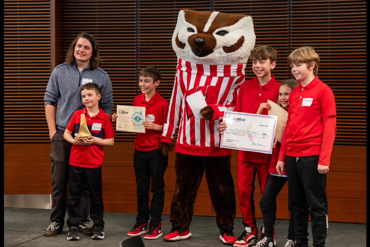 A KidWind team accepts their awards and poses for a photo with Bucky Badger