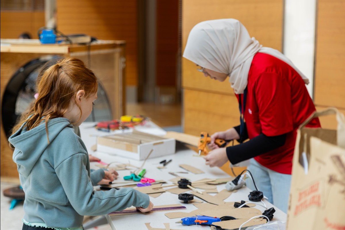 Students use cardboard and hot glue guns to make wind turbine blade prototypes during the Renewable Energy Expo.